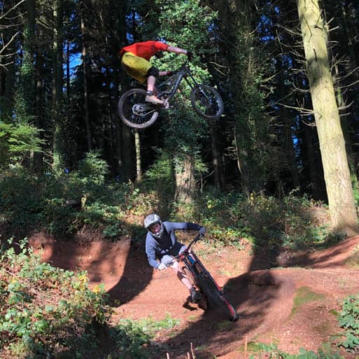 One mountain biker just casually jumping over another